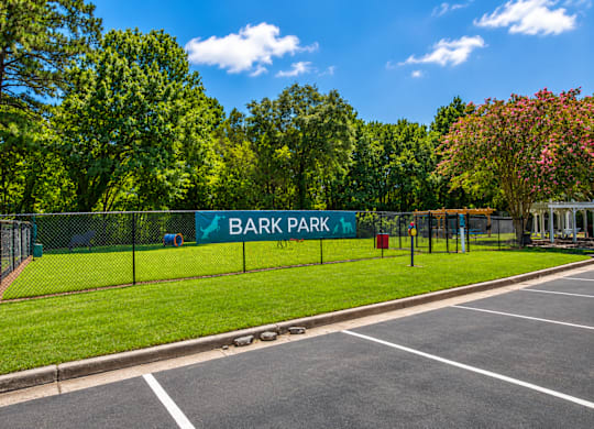 A sign that says Bark Park is on a fence.