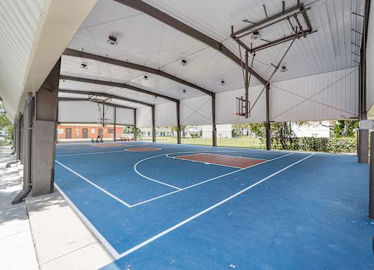 A basketball court is located under a large roof.