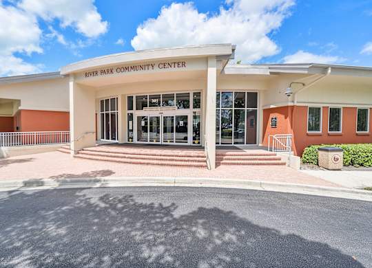The River Park Community Center is a modern building with a white and orange facade.