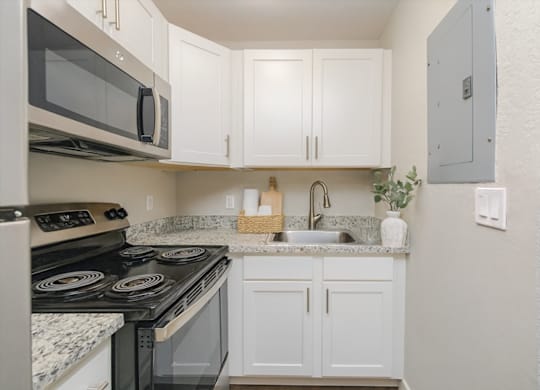A kitchen with white cabinets and a black stove top oven.