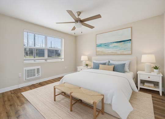 A bedroom with a large bed, a ceiling fan, and a painting on the wall.