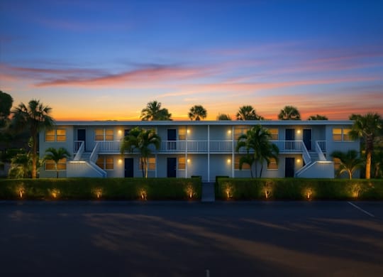 A modern building with a white exterior and palm trees in front.