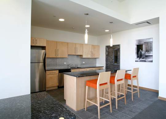 A kitchen with a black granite countertop and wooden chairs.