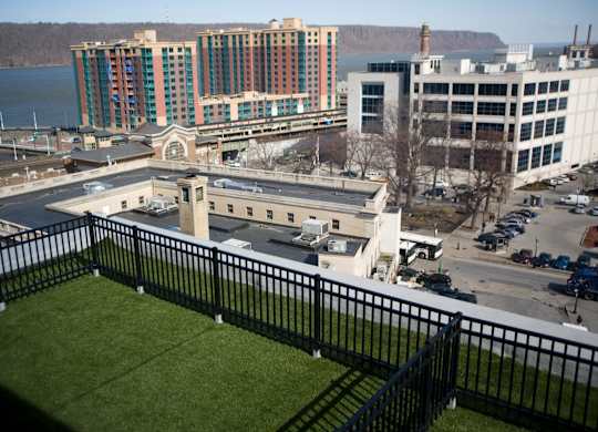 A view of a city from a balcony with a black railing.