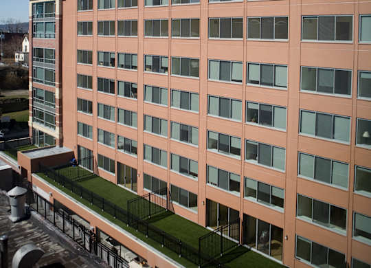 A tall building with a green lawn in the middle.