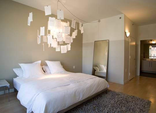 A bedroom with a bed, a mirror, and a chandelier.