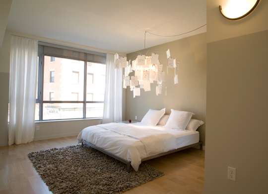 A bedroom with a large bed and a chandelier.