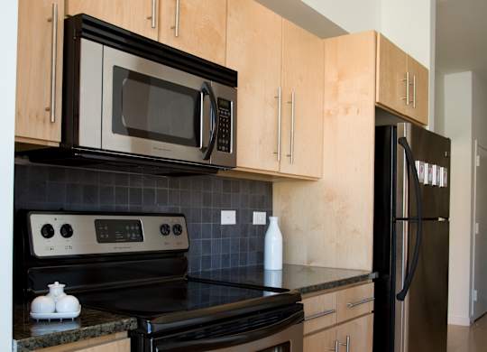 A kitchen with black appliances and wooden cabinets.