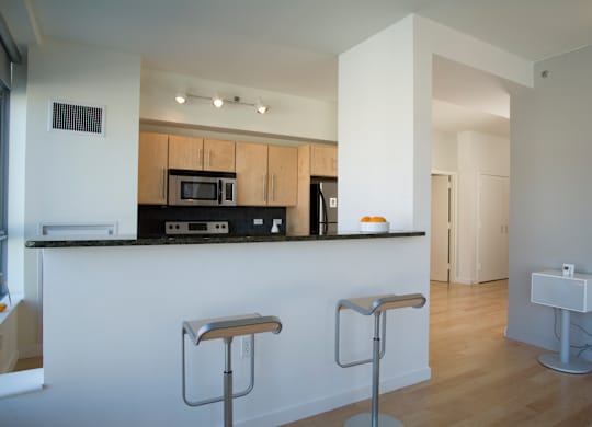A kitchen with a white counter and bar stools.
