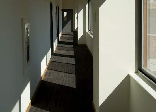 A long hallway with carpeted floors and windows on the side.