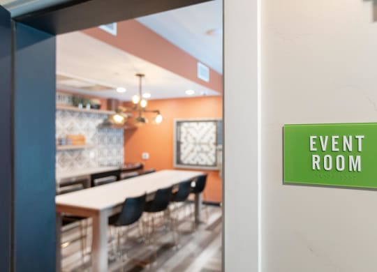 an event room with a table and chairs and a green sign that reads event room