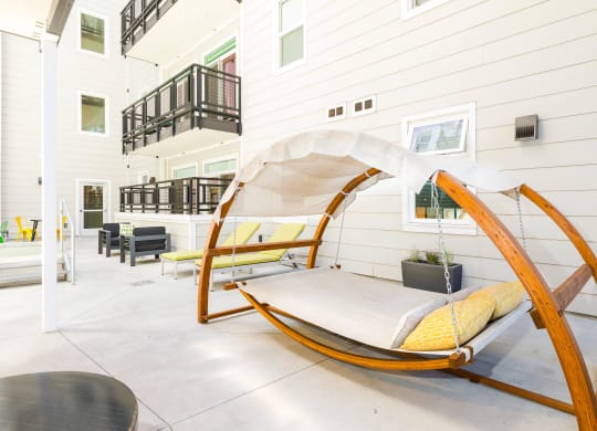 a porch swing with yellow pillows and a gray blanket