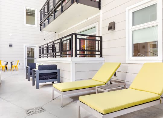 a patio with yellow lounge chairs and blue and yellow chairs