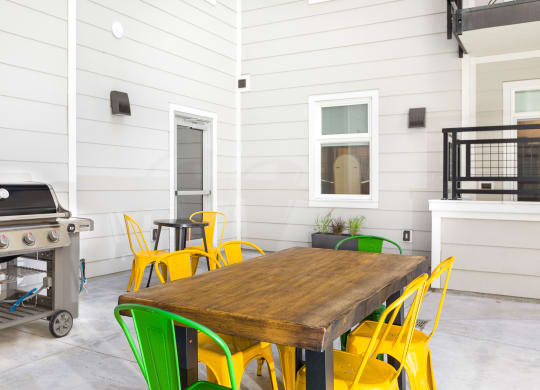 a patio with a table and chairs and a grill