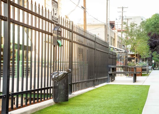a fence with a bench and trash can in front of it