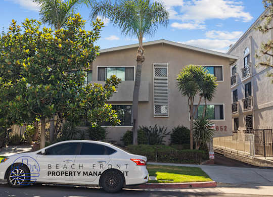 A car with Beach Front Property Management written on it is parked in front of a house.