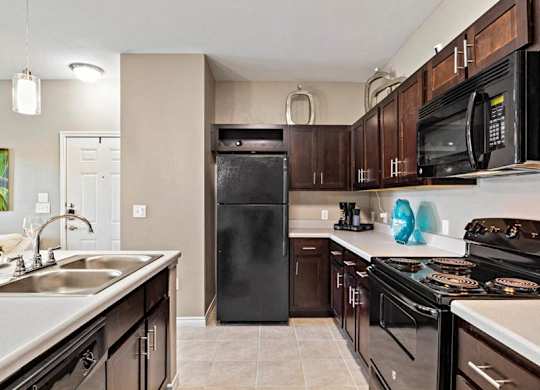 A kitchen with black appliances and brown cabinets.
