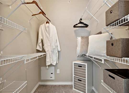 A white robe hanging on a rack in a walk-in closet.