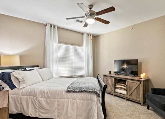 A bedroom with a bed, a chair, and a television.