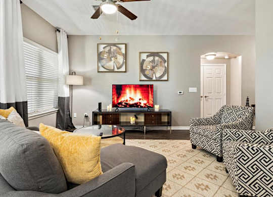 A living room with a grey couch, a fireplace, and a ceiling fan.