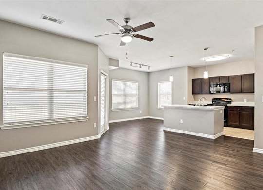 A spacious room with a ceiling fan and wooden flooring.
