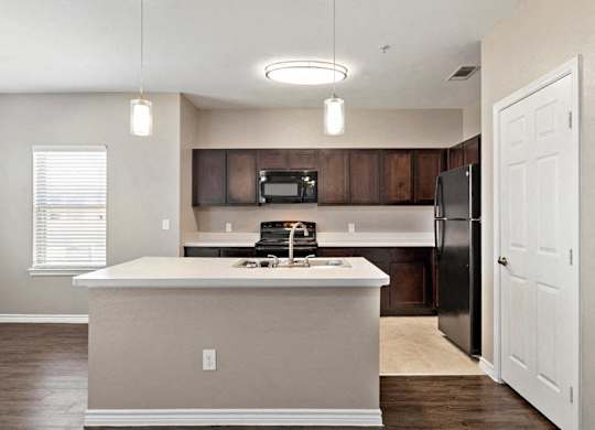A kitchen with a white island and a black refrigerator.