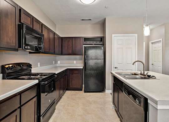 A kitchen with black appliances and brown cabinets.