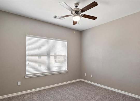 A room with a ceiling fan and a window with blinds.