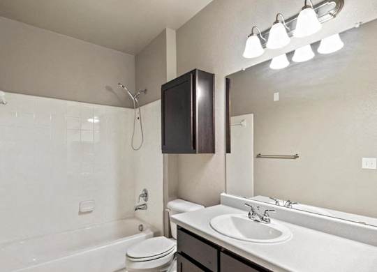 A white bathroom with a white toilet, sink, and a mirror.