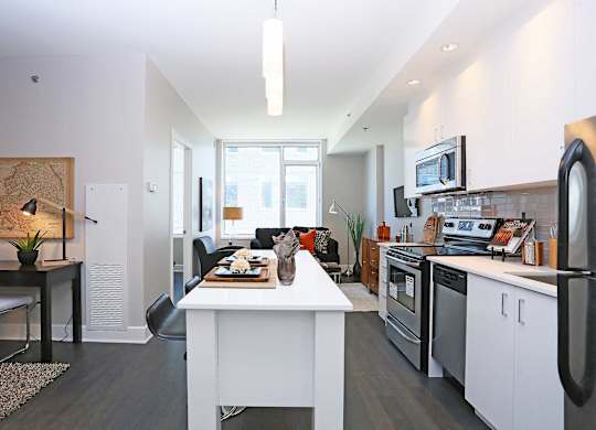 a kitchen and living room with a white counter top and appliances
