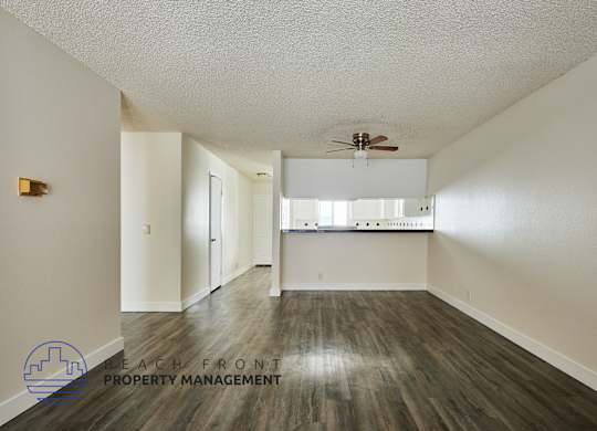 A spacious room with a ceiling fan and a logo for Beach Front Property Management.
