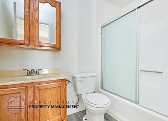 A bathroom with a toilet, sink, and mirror.