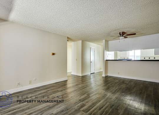 A spacious room with a ceiling fan and wooden flooring.