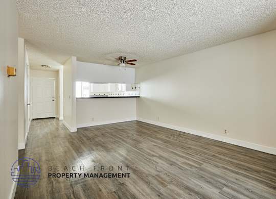 A spacious room with wooden flooring and a ceiling fan.