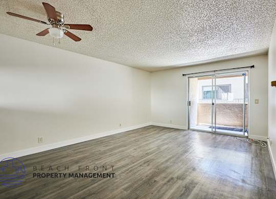 A room with a ceiling fan and a sliding glass door leading to a balcony.