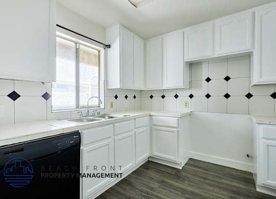 A kitchen with white cabinets and a black dishwasher.