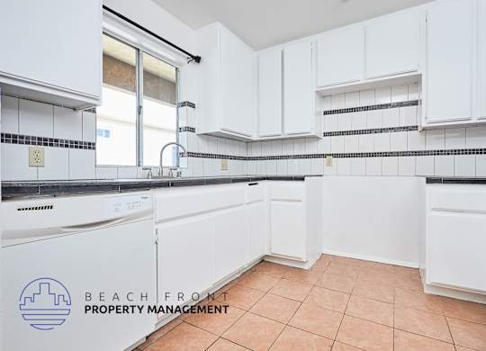 A kitchen with white cabinets and a tile floor.