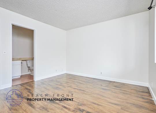 A room with wooden flooring and a logo for Beach Front Property Management.