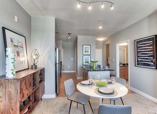 a dining area with a table and chairs and a kitchen in the background