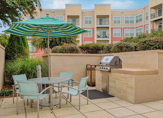 a patio with a grill and table and chairs