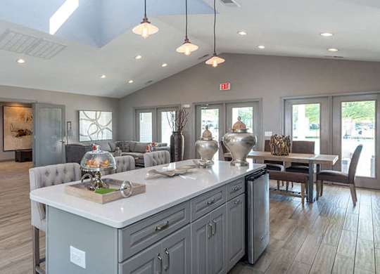 clubroom with vaulted ceilings, pendant lighting and a large island with seating