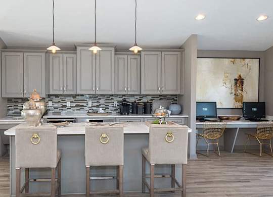 gray cabinets with large island, pendant lighting and white bar stools