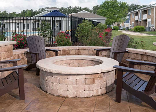 outdoor stone firepit with brown adirondack chairs