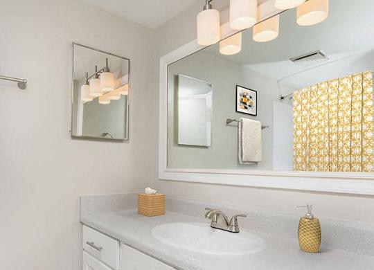 bathroom in apartment that has a large vanity, white cabinets and modern lighting