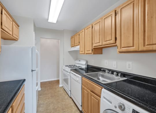 a kitchen with wood cabinets and black counter tops and white appliances