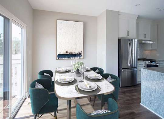 A dining room with a table set for four and a kitchen in the background.