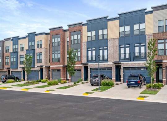 a row of new apartment buildings with cars parked in a parking lot