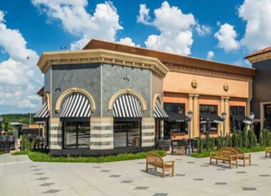 a rendering of a restaurant with tables and chairs in front of a building