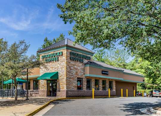 the facade of a restaurant with trees and a road
