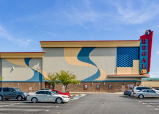 an old movie theater with cars parked in a parking lot